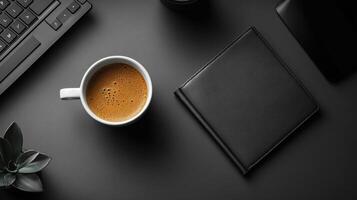 simple designers desktop featuring cup of coffee, sleek black notebook, and plant. minimalist setup creates calm and focused atmosphere for productivity photo