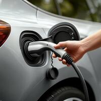 Charging electric vehicle with hand holding charging cable, showcasing eco friendly technology and modern design photo