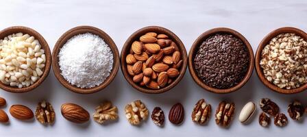 Nuts and seeds in wooden bowls, showcasing variety of textures and colors. This vibrant display includes pine nuts, coconut, almonds, flaxseeds, and chocolate sprinkles, perfect for healthy snacking photo