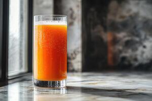 Freshly pressed carrot juice in tall glass, showcasing vibrant orange color and bubbles, set against textured background photo