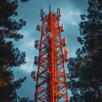 Telecommunication network tower surrounded by trees under cloudy sky. vibrant red structure features various antennas and satellite dishes, showcasing modern technology in natural setting photo