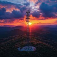telecommunication network tower stands tall against vibrant sunset, surrounded by rolling hills and dramatic clouds. scene captures beauty of technology in nature photo