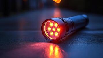red flashlight with aluminum body, featuring multiple LED lights, rests on wet surface, reflecting ambient light. Its design is practical and durable, ideal for various uses photo