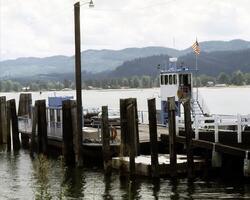 Serene Lake Scene with Boat Docked Beneath a Cloudy Sky and Majestic Mountains photo
