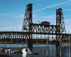 Serene Lake Scene with Boats Under a Cloudy Sky and a Girder Bridge in the Background photo
