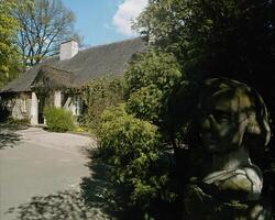 Serene Landscape with a Thatched House, Tree, and Cloudy Sky photo
