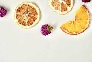Dry globe amaranth, lemon, and orange fruit slices isolated on horizontal copy spaced white background. photo
