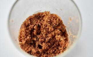 Beef meat floss or abon sapi in glass container isolated on horizontal white background. photo