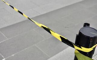 Yellow and black striped lines tape. Do not enter or cross barrier fence object isolated on horizontal gray concrete flooring background. photo