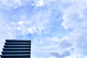 Office tower building exterior isolated on horizontal blue cloudy daytime sky background. photo