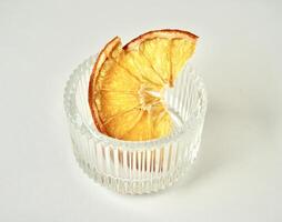 Sliced in half dried orange fruit in small round glass bowl container isolated on horizontal white background. photo