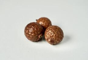 Decorative three brown round nuts with snake fruit skin shape object isolated on white background. photo