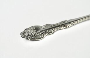 Close up decorative silver spoon tableware object handle isolated on horizontal white background. photo