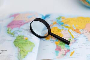 Magnifying glass on atlas map, symbolizing travel search, geography exploration, global discovery, and navigation planning photo