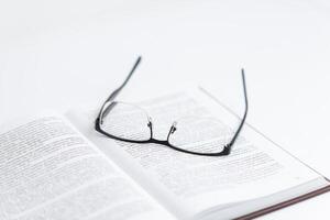 Glasses resting on open book with text, symbolizing reading, research, science, and law study, representing focused exploration of knowledge and academic or legal studies photo