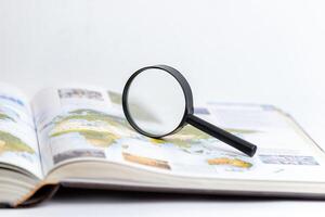Magnifying glass on open book symbolizing search, research, and in-depth exploration of knowledge and information, emphasizing discovery and detailed analysis in learning and studying contexts photo