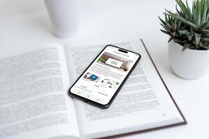 Phone displaying online courses app on a book, symbolizing creative writing education. Ideal for visuals on digital learning, writing skills, online courses, and education tools. photo