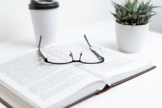 Open book with glasses resting on top, symbolizing reading, knowledge, study, and insight, representing concepts of learning, literature, wisdom, and intellectual exploration photo