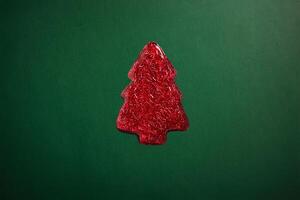 red sparkly jelly shaped like a Christmas tree on green background. Minimalistic holiday photo