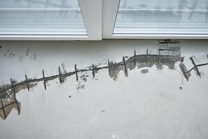 Repairing cracks in concrete floor near window using sealant. Renovation process in house under construction photo