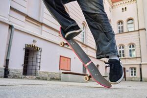Skateboarder doing ollie trick at urban street. Close up of skater wearing baggy jeans balancing on skateboard. Concept of youth subculture photo