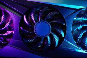 Close-up of high-performance graphics card with cooling fans illuminated by neon lighting. Modern card for gaming and advanced computing photo