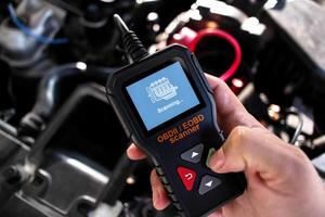 OBDII Scanner in use under the hood by auto mechanic for reading fault code of the car engine system , Car repair concept photo