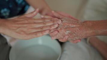 A close-up captures the tender moment of a younger hand gently holding the weathered hand of an elderly person, symbolizing love, care, and connection across generations. video