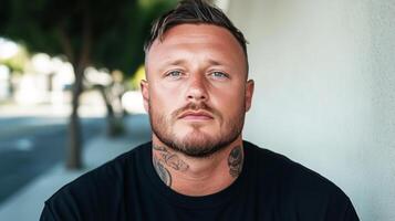 Serious man with neck tattoos posing in urban setting photo
