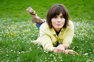 Young woman relaxing in field of daisies enjoying spring season photo