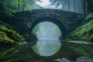Old stone bridge reflecting in the calm river in a misty forest photo