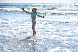 An 8 year old girl in a swimsuit having fun in the sea waves. photo