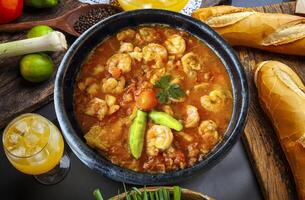 A bowl of stew with shrimp and vegetables on a table photo