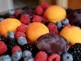 Colored background of seasonal summer fruits apricot, plum, raspberry, blueberry, blackberry in garden, close up photo