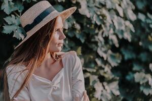Woman with straw hat stands in front of vineyard. She is wearing a light dress and posing for a photo. Travel concept to different countries photo