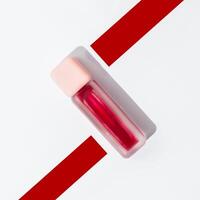 A red liquid bottle with a red strip on top photo