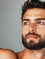 Thoughtful young man with a beard gazes into the distance indoors photo
