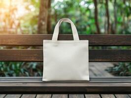 A simple white tote bag resting on a wooden bench in a lush garden photo