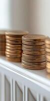 Stacked golden coins arranged neatly on a white shelf photo