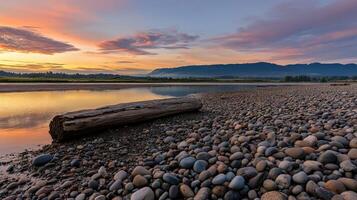 Sunset over a serene river with smooth pebbles lining the shore photo