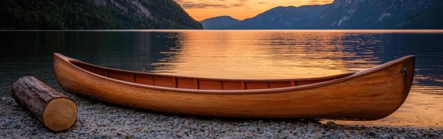 Sunset over tranquil lake with wooden canoe on shoreline photo