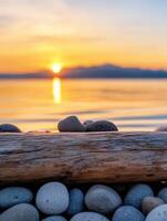 Serene sunset over calm water with pebbles and driftwood photo