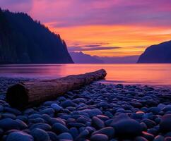 Vibrant sunset over tranquil shoreline with log and pebbles photo