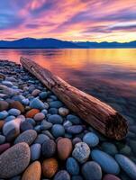 Colorful sunset over calm waters with a log and stones photo