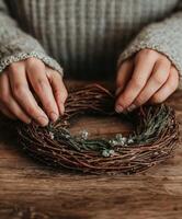 Creating a natural wreath with hands on a wooden surface photo