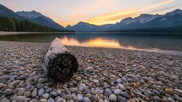 Sunset over a tranquil lake with mountain backdrop and pebbled shore photo