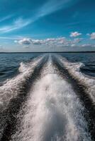 Scenic view of boat wake on tranquil lake under blue sky photo
