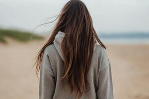 Woman with long hair walking on a sandy beach during cloudy weather photo
