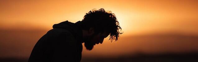 Man in silhouette against vibrant sunset sky during evening contemplation photo