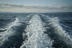 Waves create white water trails on a calm ocean during daytime photo